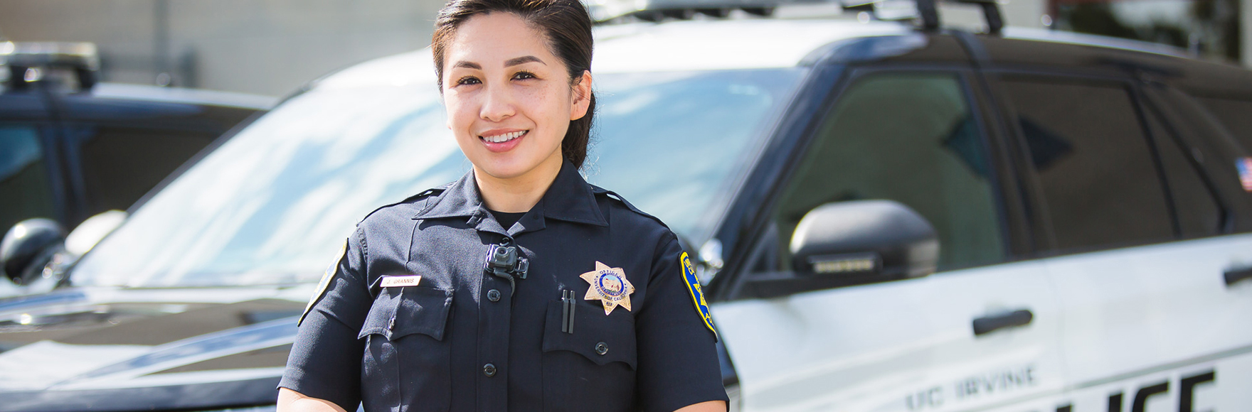 Officer Grannis smiling in front of a police car