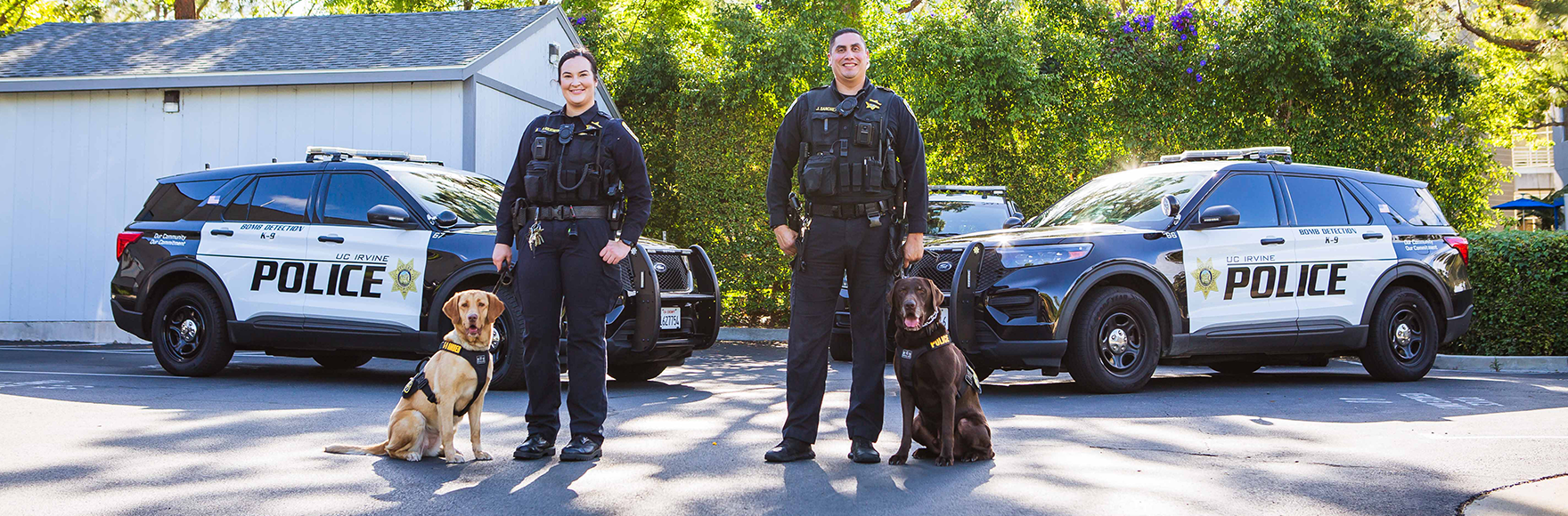 K-9 handlers posing in front of cars and smiling