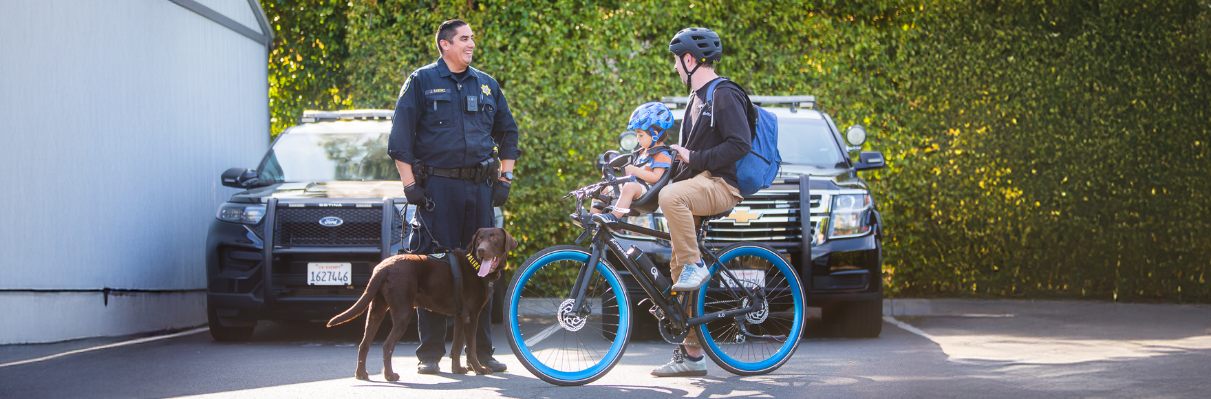 Officer Sanchez and K-9 Cliff greets a UCI community member